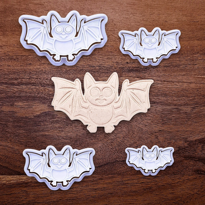 Bat cookie cutters with matching stamps and dough cutout with bat design pressed by cutter and stamp set, showing detailed lines—great for easy Halloween cookie decorating without icing.