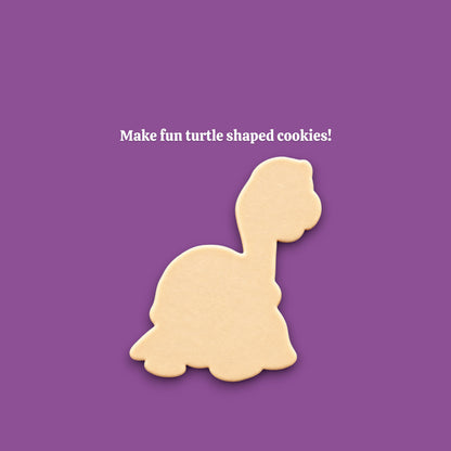 A turtle-shaped cookie centered on a solid purple background, with white text above reading 'Make fun turtle shaped cookies!'.