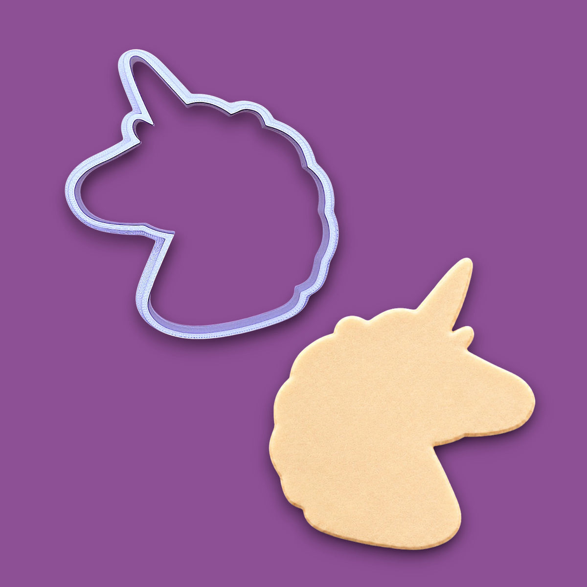 A unicorn-shaped cookie cutter outline and a matching cutout cookie shown on a solid purple background.