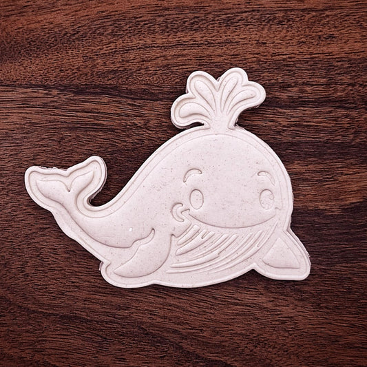 Stamped whale-shaped cookie dough cutout showing detailed fins, tail, and facial features—great for themed baking and decorating.